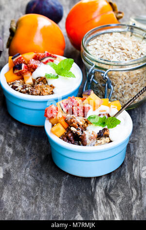 Crumble de fruits avec des flocons d'avoine et kaki et figure sur la table rustique en bois Banque D'Images