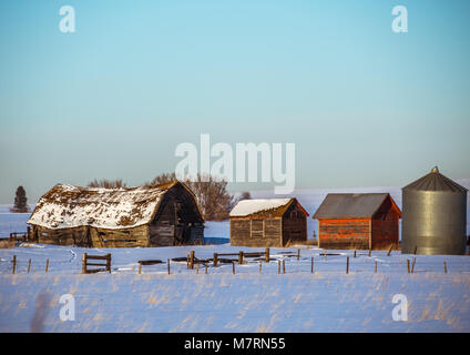 Belles anciennes granges dans le champ neigeux capturé au coucher du soleil Banque D'Images