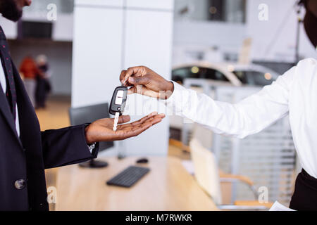 Jeune femme africaine voiture vendeur donnant une clé à partir de la nouvelle voiture à la belle jeune couple propriétaire Banque D'Images