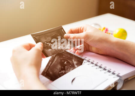 Femme de placer bébé sonogramme dans la première année du bébé livre mémoire Banque D'Images