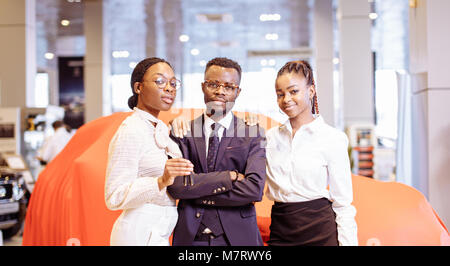 Vendeur de voiture d'Afrique et deux femme montrant les principaux de nouvelle voiture Banque D'Images