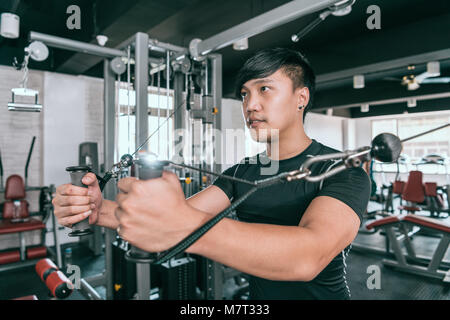 Man working out in gym faisant voler sur tour à commandes par câble. Exercice pour les muscles de la poitrine. Banque D'Images