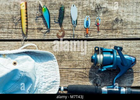 Objets pour la pêche sur une jetée en bois close-up - les hameçons, les appâts, bobine et hat Banque D'Images