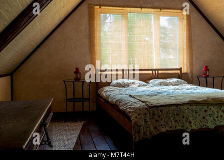 Chambres à proximité d'une fenêtre dans une chambre au dernier étage d'une maison en bois, sous un toit Banque D'Images