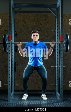 Avec un bodybuilder barbell dans la salle de sport est la pratique Banque D'Images