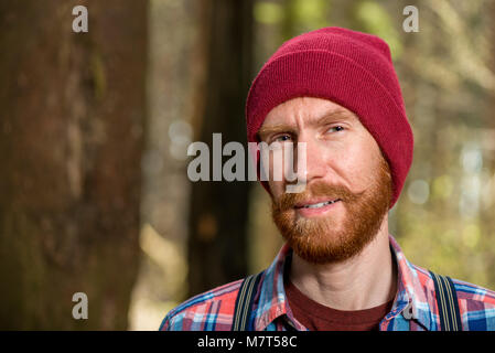Portrait d'un hipster avec une barbe rouge close-up dans la forêt Banque D'Images