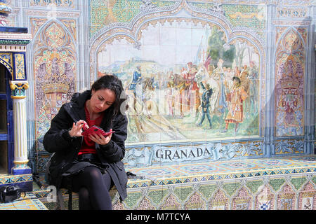Contrôle de femme son téléphone assis dans une alcôve provincial à la Plaza de España à Séville Banque D'Images
