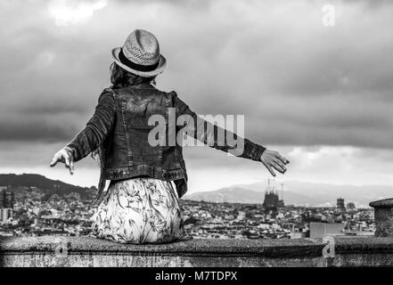 Soirée parfaite avec vue magnifique. Vus de derrière, jeune voyageur femme en robe et chapeau de paille dans l'avant du paysage urbain de Barcelone, Espagne r Banque D'Images