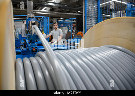 08 mars 2018, l'Allemagne, l'Stuttgart-Vaihingen : Un employé du fabricant de câble Lapp supervise l'enroulement d'un câble. Lapp ont profité de la hausse des prix pour le cuivre dans la dernière année. L'entreprise familiale qui appartient à le premier fabricant mondial des câbles industriels, va avoir son état financier (conférence de presse le mardi 13 mars 2018) à Stuttgart. Photo : Sina Schuldt/dpa Banque D'Images