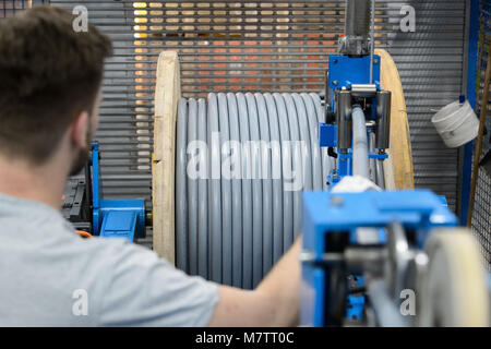 08 mars 2018, l'Allemagne, l'Stuttgart-Vaihingen : Un employé du fabricant de câble Lapp supervise l'enroulement d'un câble. Lapp ont profité de la hausse des prix pour le cuivre dans la dernière année. L'entreprise familiale qui appartient à le premier fabricant mondial des câbles industriels, va avoir son état financier (conférence de presse le mardi 13 mars 2018) à Stuttgart. Photo : Sina Schuldt/dpa Banque D'Images