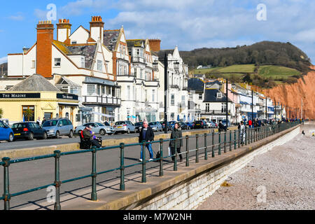 La ville de Sidmouth, Devon, UK. 13 mars 2018. Météo britannique. Les visiteurs et les résidents bénéficiant d'une promenade le long du front de mer de la station balnéaire de Sidmouth dans le Devon par une chaude après-midi de printemps ensoleillé. Crédit photo : Graham Hunt/Alamy Live News. Banque D'Images