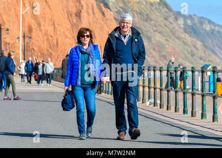 La ville de Sidmouth, Devon, UK. 13 mars 2018. Météo britannique. Les visiteurs et les résidents bénéficiant d'une promenade le long du front de mer de la station balnéaire de Sidmouth dans le Devon par une chaude après-midi de printemps ensoleillé. Crédit photo : Graham Hunt/Alamy Live News. Banque D'Images