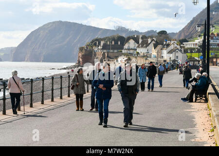 La ville de Sidmouth, Devon, UK. 13 mars 2018. Météo britannique. Les visiteurs et les résidents bénéficiant d'une promenade le long du front de mer de la station balnéaire de Sidmouth dans le Devon par une chaude après-midi de printemps ensoleillé. Crédit photo : Graham Hunt/Alamy Live News. Banque D'Images