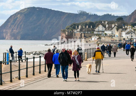 La ville de Sidmouth, Devon, UK. 13 mars 2018. Météo britannique. Les visiteurs et les résidents bénéficiant d'une promenade le long du front de mer de la station balnéaire de Sidmouth dans le Devon par une chaude après-midi de printemps ensoleillé. Crédit photo : Graham Hunt/Alamy Live News. Banque D'Images