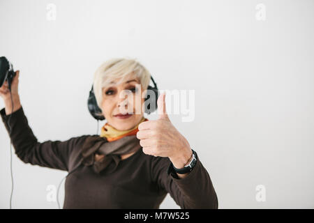 Une femme âgée joue un jeu vidéo et les gestes qu'elle a gagné. Personne âgée et la technologie moderne. Banque D'Images