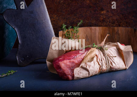 La viande crue. Un grand morceau de marbre sur le pavé de boeuf chop avec assaisonnement, sur une table. Close up Banque D'Images