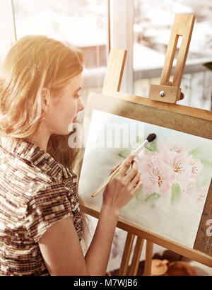 Artiste peinture sur chevalet dans Studio. Les peintures de fille avec un pinceau. Banque D'Images