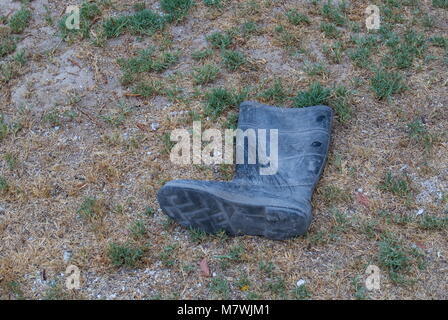 Unique en caoutchouc jetés sale gumboot isolés sur une image de fond à l'extérieur au format paysage with copy space Banque D'Images