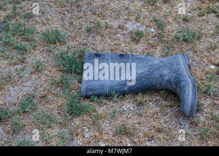 Unique en caoutchouc jetés sale gumboot isolés sur une image de fond à l'extérieur au format paysage with copy space Banque D'Images