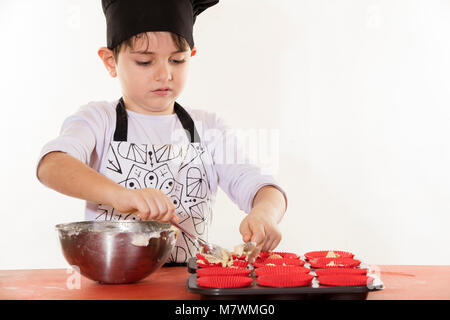 Vêtements mignon petit garçon chef préparer cupcakes Banque D'Images