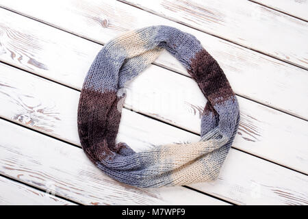 Écharpe en laine coloré arrondi. La surface d'un bureau en bois blanc, arrière-plan. Banque D'Images