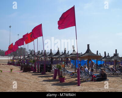 AGADIR, Maroc afrique sur février 2017 : Rouge drapeaux marocains et des parasols sur la plage paysages en ville voyage avec ciel bleu clair en hiver ensoleillé chaud Banque D'Images