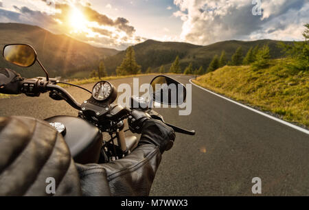 POV de motorbiker maintenant le bar, équitation dans Alpes en beau coucher du soleil Ciel dramatique. Et la liberté de déplacement, activités en plein air Banque D'Images