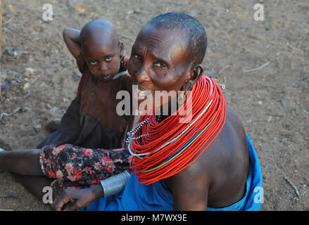 Portrait d'une mère non identifiés et de l'enfant, vêtu d'ornement traditionnel collier de perles rouges, se trouve à l'extérieur hut dans village local. Banque D'Images