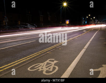 L'exposition lente du milieu de la route de nuit avec des feux du véhicule en passant par Banque D'Images