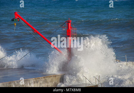 La grue rouge sur le quai avec l'état de la mer Banque D'Images