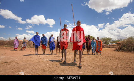 Inconnu Masai village près de parc Amboselli, Kenya - Avril 02, 2015 : les guerriers Masaï la queue pour la danse traditionnelle et le chant avec ciel bleu profond Banque D'Images