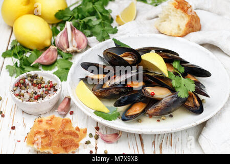 Moules au vin blanc délicieux avec du citron, l'ail, les herbes et les épices dans une assiette blanche. Baguette, la coriandre et le poivre. Les fruits de mer. Les palourdes dans les coquilles. Sn Banque D'Images