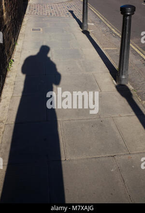 Une longue ombre de figure dans la rue en plein soleil Banque D'Images