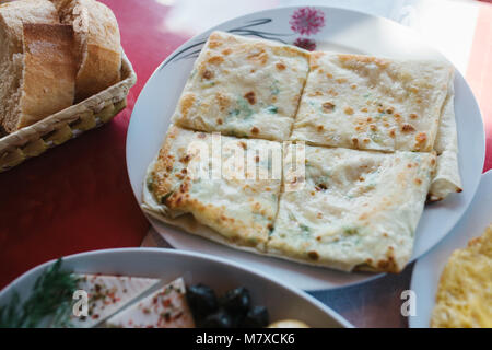 Close-up : galette aux herbes divisé en quatre pièces, morceau d'assiette de légumes et des morceaux de pain Banque D'Images