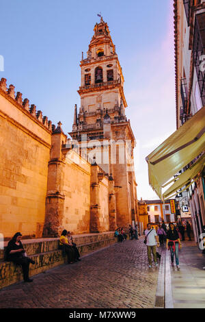 Cordoue, Andalousie, Espagne : les gens passent devant le clocher et façade nord de la mosquée-cathédrale de Cordoue au crépuscule. Banque D'Images