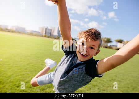 Close up of garçon sautant dans l'air à un parc. Joyeux garçon aime être levé dans l'air tout en jouant dans un parc. Banque D'Images