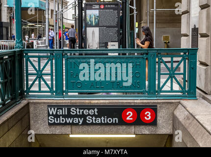 Une femme vérifie son téléphone près d'une entrée de la station de métro de Wall Street, Lower Manhattan, New York Banque D'Images