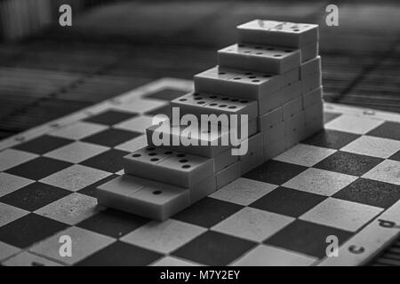 Pyramide monochrome de pièces domino sur la table en bois bambou brown background Banque D'Images