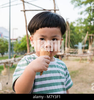 Happy kid boy eating ice cream dans le parc Banque D'Images