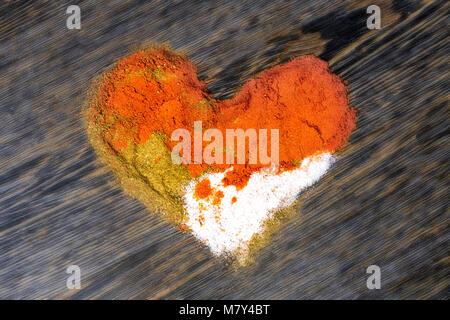 Coeur fait d'épices (sel de l'Himalaya, le poivre, le paprika) sur un fond de bois Banque D'Images