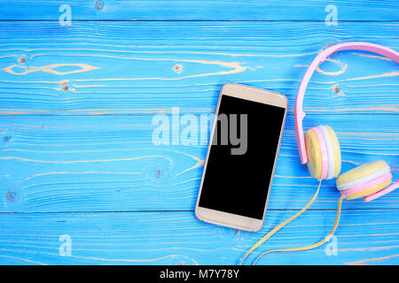 Vue supérieure, smartphone et nouveau casque musique rose moderne sur fond bleu planche en bois. Avec un espace réservé au texte ou dessin Banque D'Images