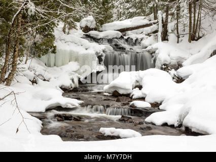 Chute d'eau en hiver. Wagner Falls à Munising Michigan, entouré de neige fraîchement tombée. Les lignes de la neige des branches d'arbre et de la dentelle, la glace du châssis w Banque D'Images