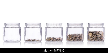 Thai baht (monnaie) en pot de verre clair avec différents niveaux de moins à plus. Studio shot isolé sur fond blanc. Économiser de l'argent ou d'investissement financi Banque D'Images