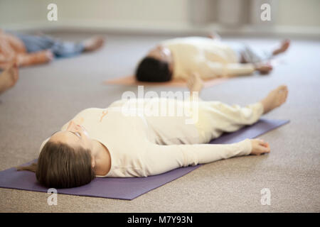 Deux jeunes gens pratiquant également appelée relaxation yoga nidra. En pose shavasana sur leur dos, sur leur tapis de yoga en cours de piscine en li Banque D'Images