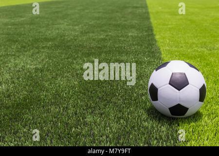 Ballon de football classique et lumineuse artificielle sur herbe vert foncé à l'extérieur du public du stade de football ou de futsal Banque D'Images