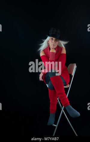 Auto-portrait du photographe dans un style minimaliste poser assis dans de grands cheveux président levée par une douce brise. A young woman wearing hat gris et noir Banque D'Images