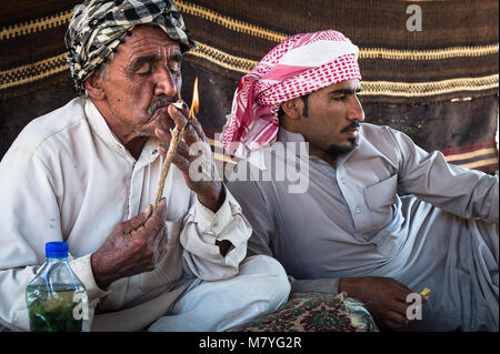 Deux man smoking a sigaret et relaxant dans leur tente bédouine dans le Wadi Rum en Jordanie. Banque D'Images