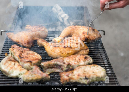 Homme fry de cuisses de poulet et des steaks sur le grill, reste avec des amis à l'air libre, la cuisine Banque D'Images