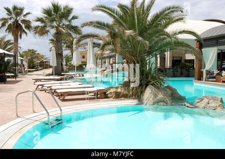 Palmiers, un pont et des piscines aux eaux turquoises dans un hôtel moderne grecque. Banque D'Images