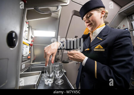 08 mars 2018, l'Allemagne, Francfort : Lufthansa flight attendant Mme Meyer prépare des verres de boissons pour l'embarquement des passagers d'un Airbus A 321 avions de passagers à l'aéroport de Francfort. À l'occasion de la Journée internationale de la femme tous les postes opérationnels de vol Lufthansa LH 174 y compris les membres de l'équipage de cabine, cockpit et sur l'aire sont dotés par des femmes. La seule exception est le chargement des bagages et l'expédition, qui est encore composé d'hommes en raison de problèmes de santé et sécurité au travail règlements. Photo : Fabian Sommer/dpa Banque D'Images